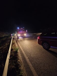 Feuerwehrfahrzeug und Einsatzkräfte bei einem nächtlichen Einsatz auf der Landstraße.