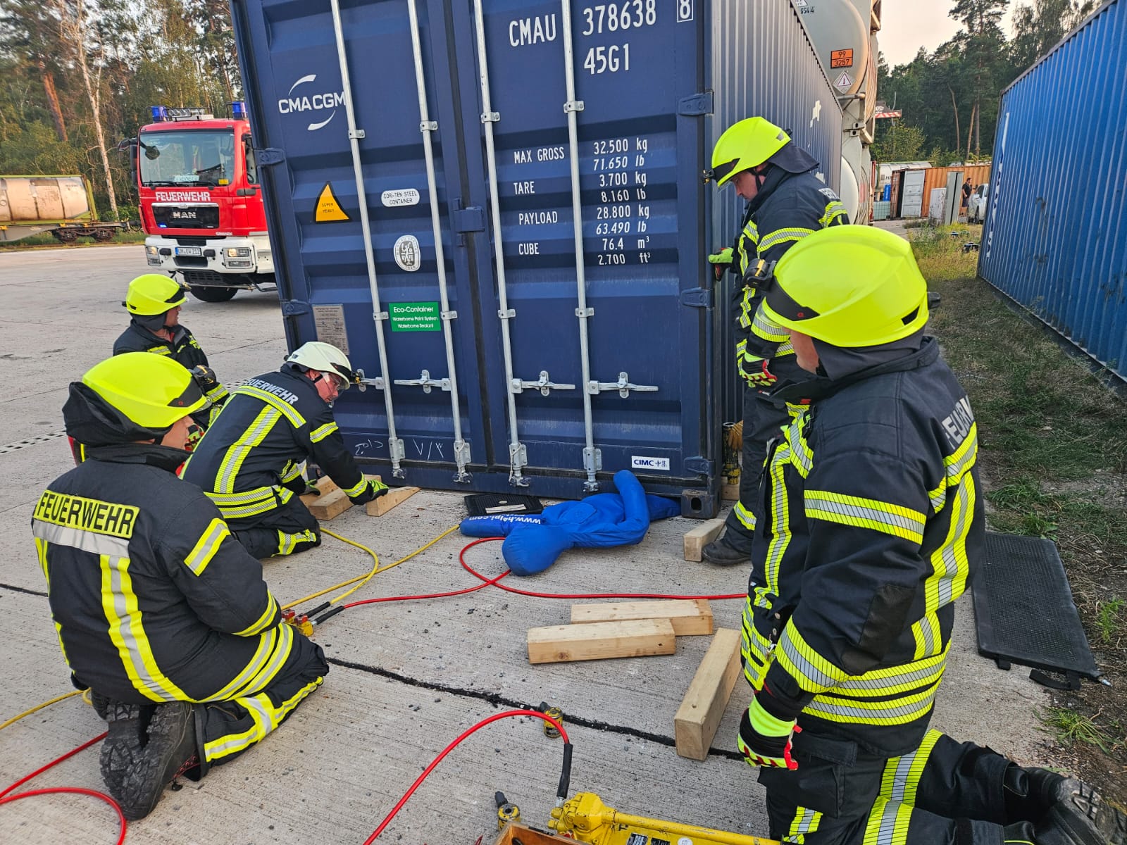 Feuerwehrleute trainieren mit Container und technischem Gerät.