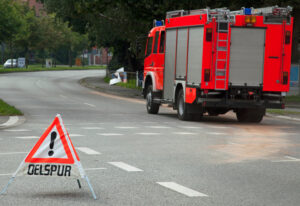 Feuerwehrauto hinter Ölspur-Warnschild auf Straße.