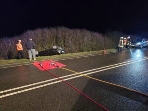 Verkehrsunfall mit umgestürztem Auto auf dunkler Straße.