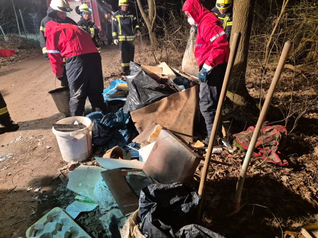Feuerwehrleute entsorgen illegalen Müll im Wald.